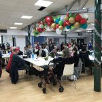 people of all ages surround the tables in surbiton school